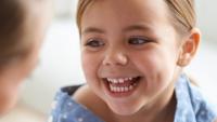 Young child smiles at neurologist during exam.